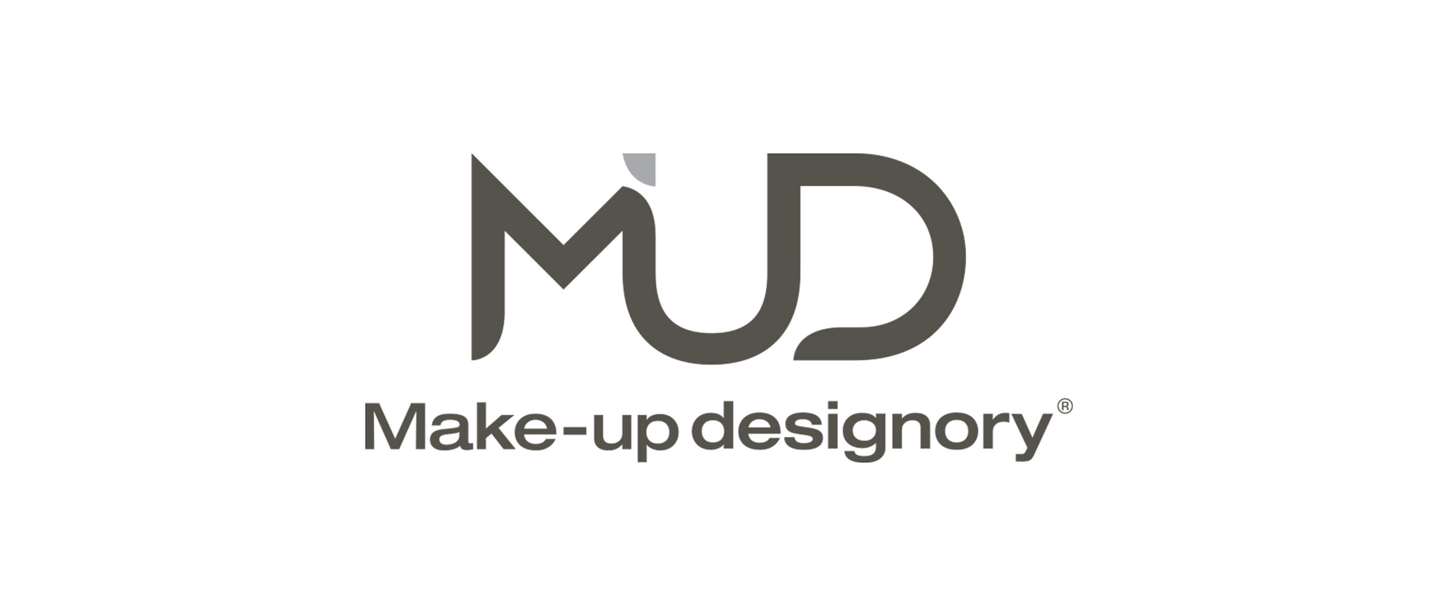 Grey text logo featuring stylized “MUD” lettering above the words “Make-up designory.”
