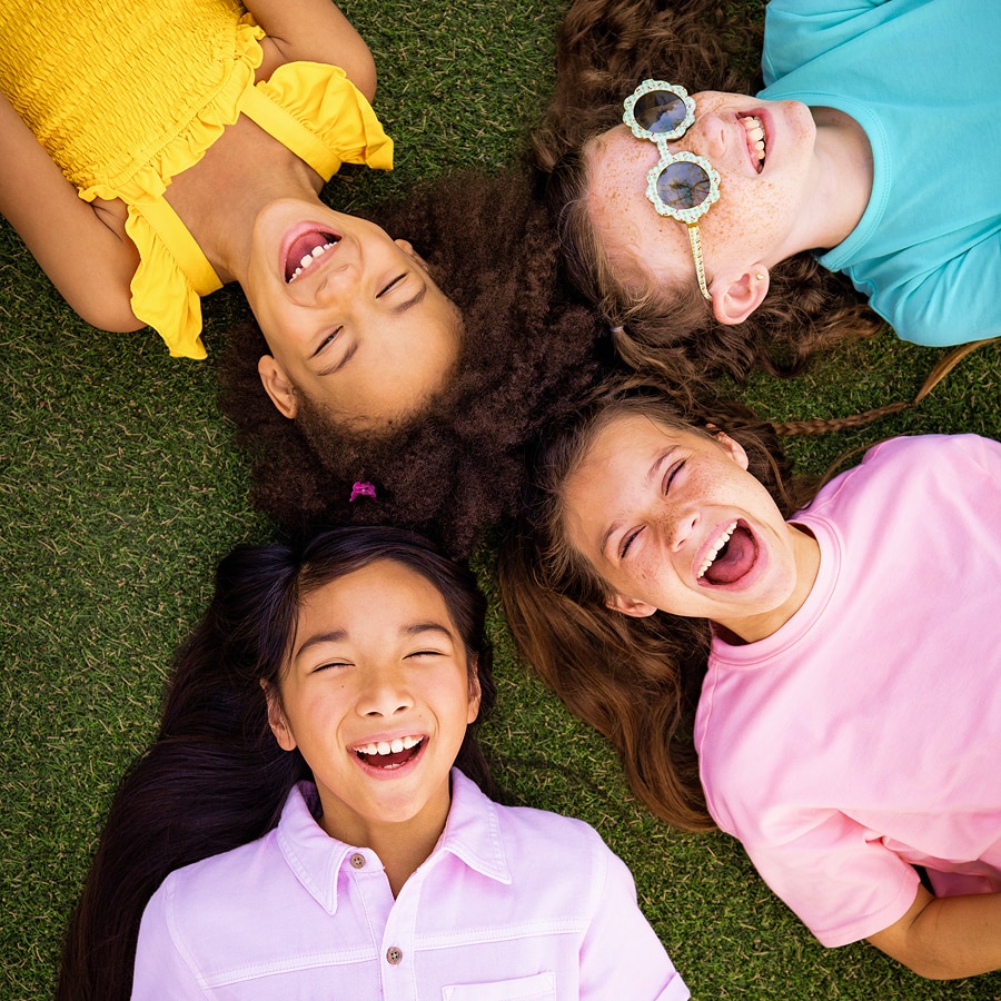 Four girls lay in the grass laughing at Universal Kids Resort.