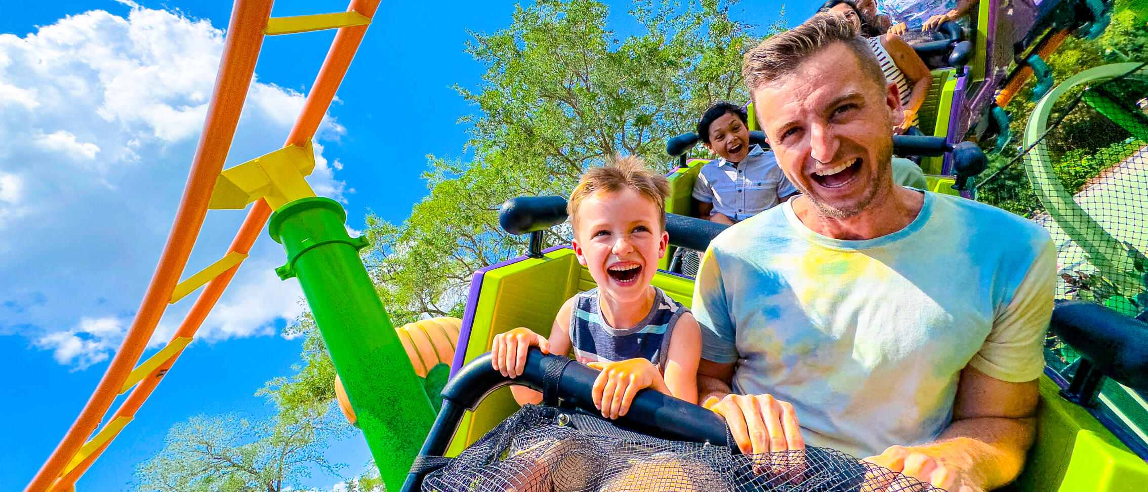 Guests smiling in excitement as they ride the Trolls Coaster in DreamWorks Land.
