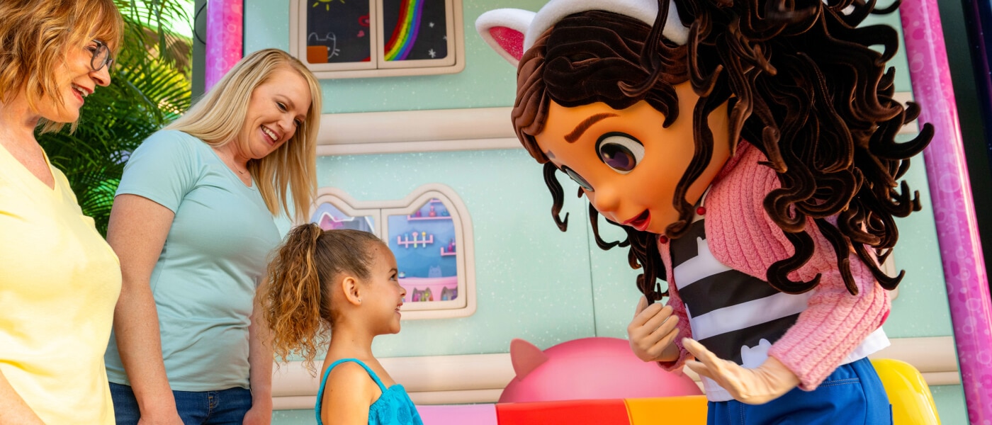 Una niña y su familia se reúnen con Gabby en su casa de muñecas.