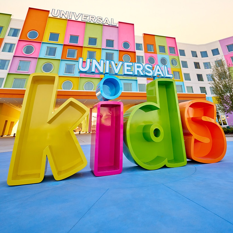 Foto del exterior de Universal Kids Resort. Al frente, hay un letrero colorido de tamaño real que dice KIDS