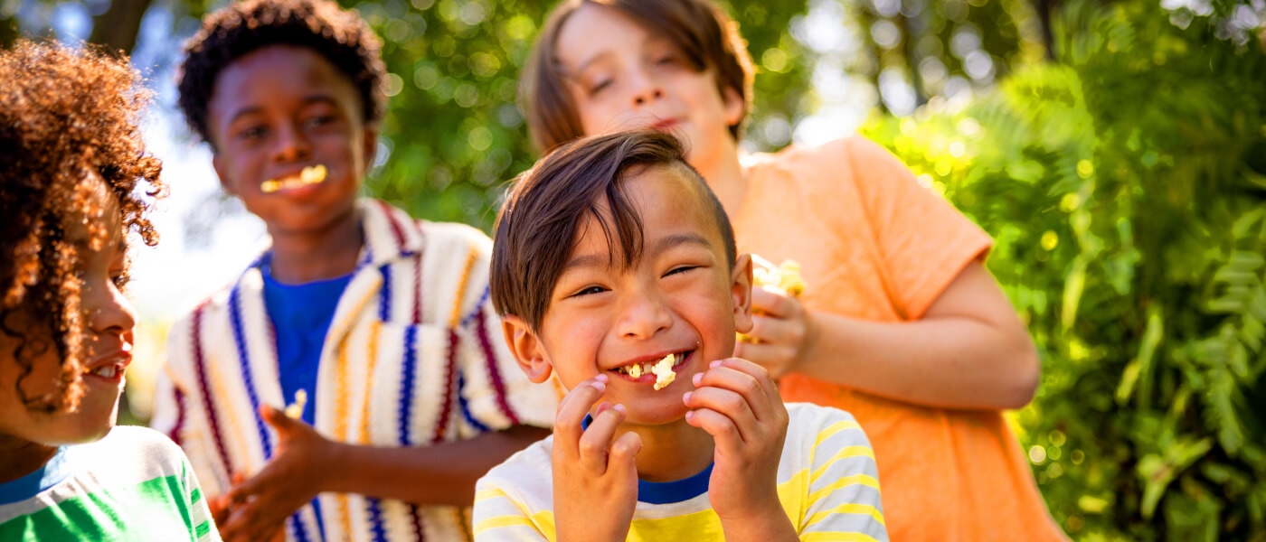 Un grupo de niños sonriendo mientras comen palomitas de maíz.