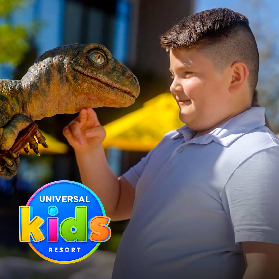 Un niño sonríe mientras toca a un raptor bebé durante un encuentro interactivo en Universal Kids Resort.