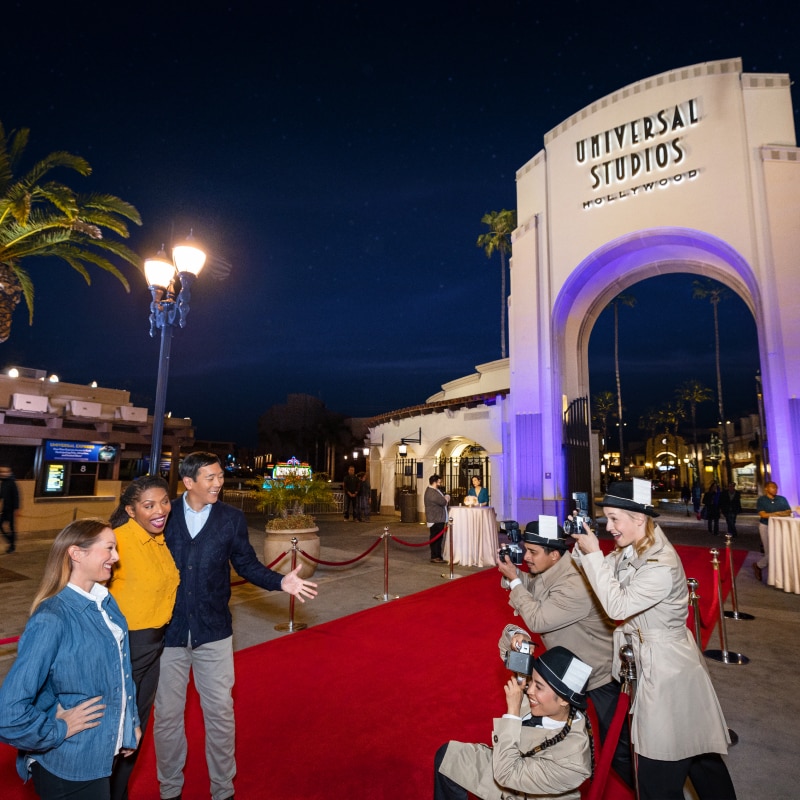 Guests posing for a photo on the red carpet in front of the entrance to Universal Studios Hollywood.