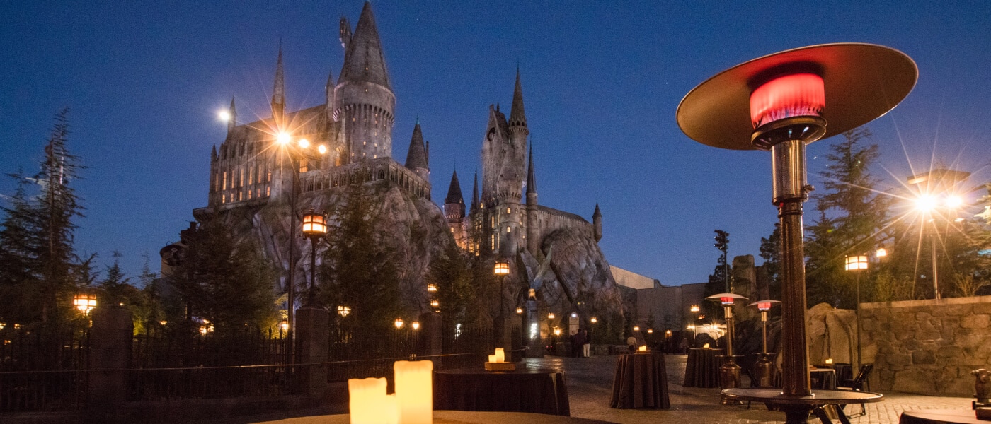 Evening event setup with cocktail tables and patio heaters in front of Hogwarts castle.
