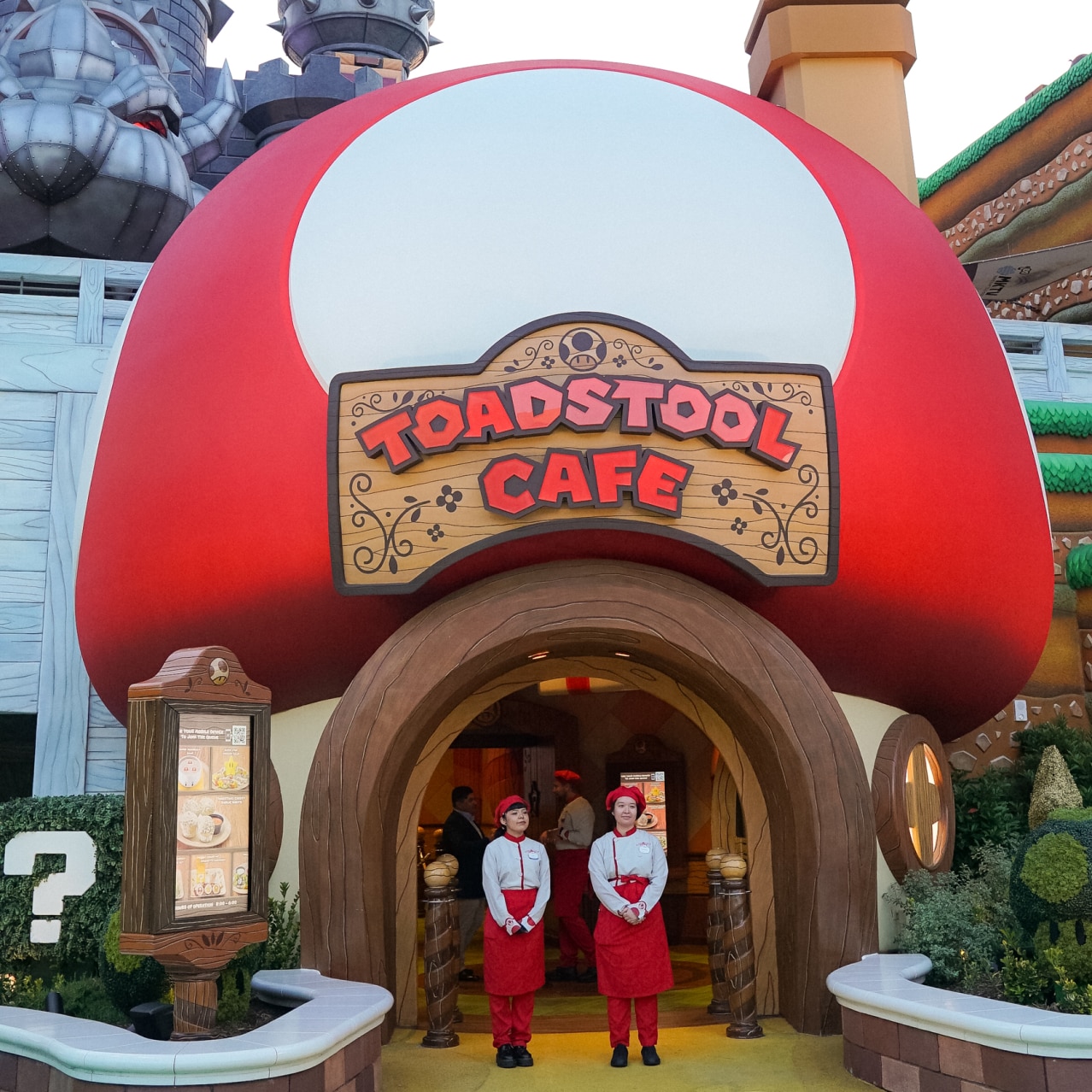 Two servers standing in front of the Toadstool Cafe™.