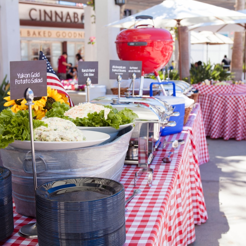 Tables with red checkered tablecloths and a buffet style spread set up for an event inside of Universal Plaza.