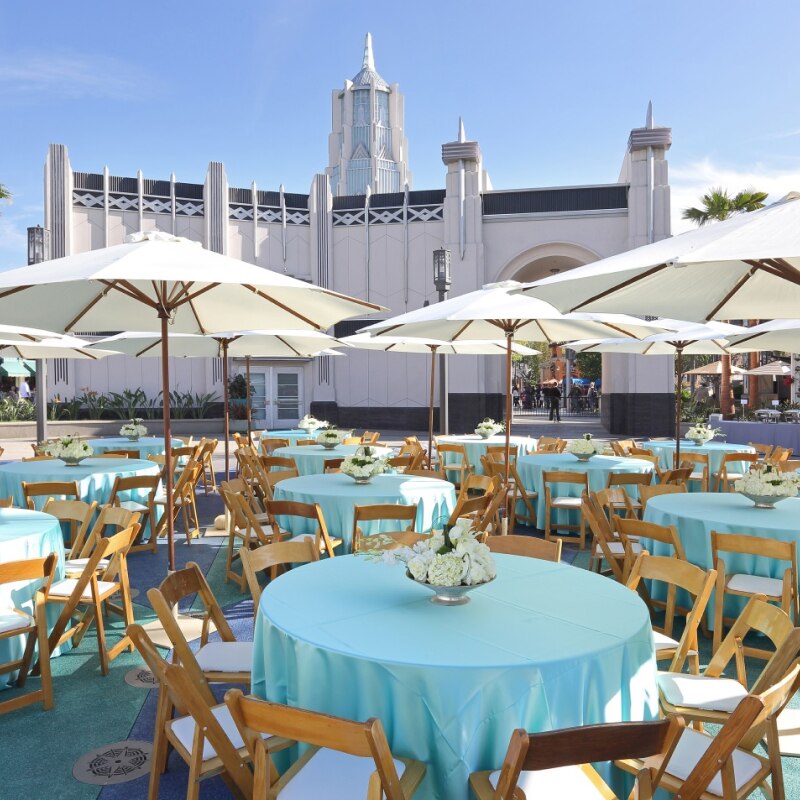 Tables with teal tablecloths and floral centerpieces set up for an event inside of Universal Plaza.