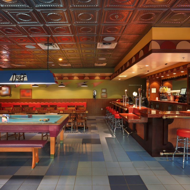 A pool table next to the bar inside of Moe's Tavern.
