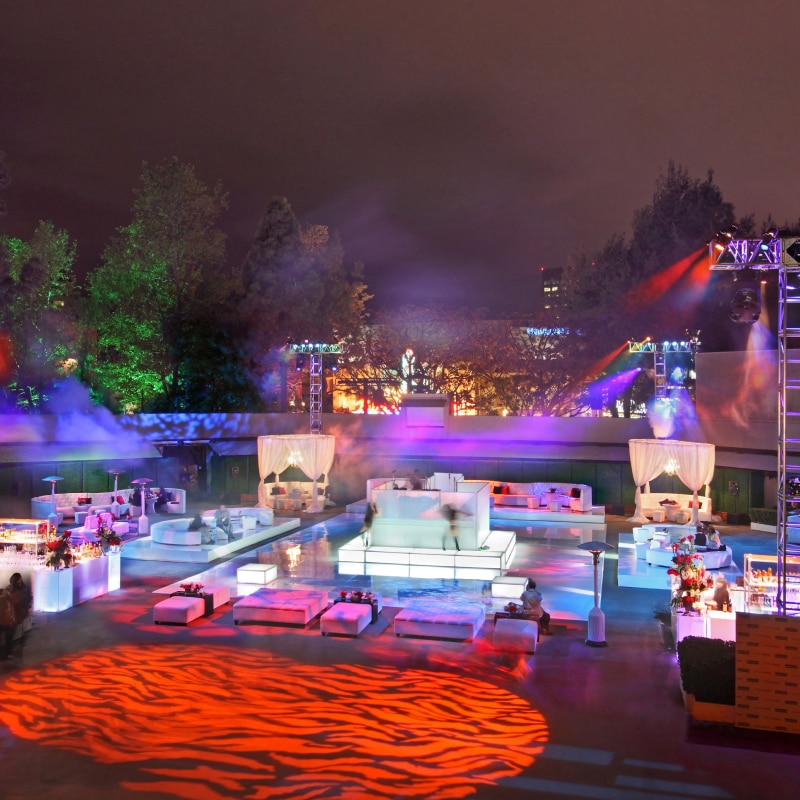 An aerial view of an event set up with tables, chairs and colorful lights.