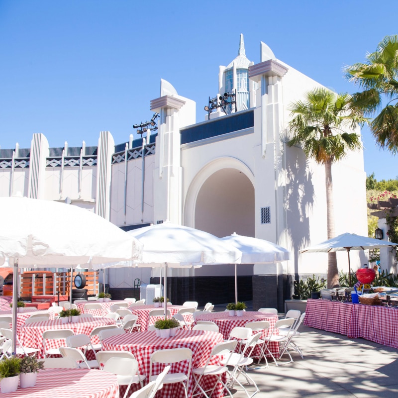 Tables and chairs with umbrellas set up next to a buffet style spread near the Universal Studios Hollywood entrance.