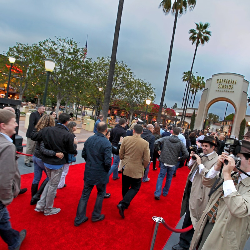 Guests attending an event walking down the red carpet leading to the entrance of Universal Studios Hollywood.