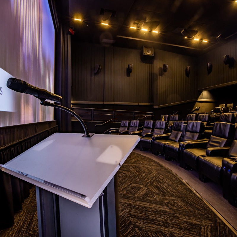 A podium set up in front of a movie theater screen inside Universal Cinema.