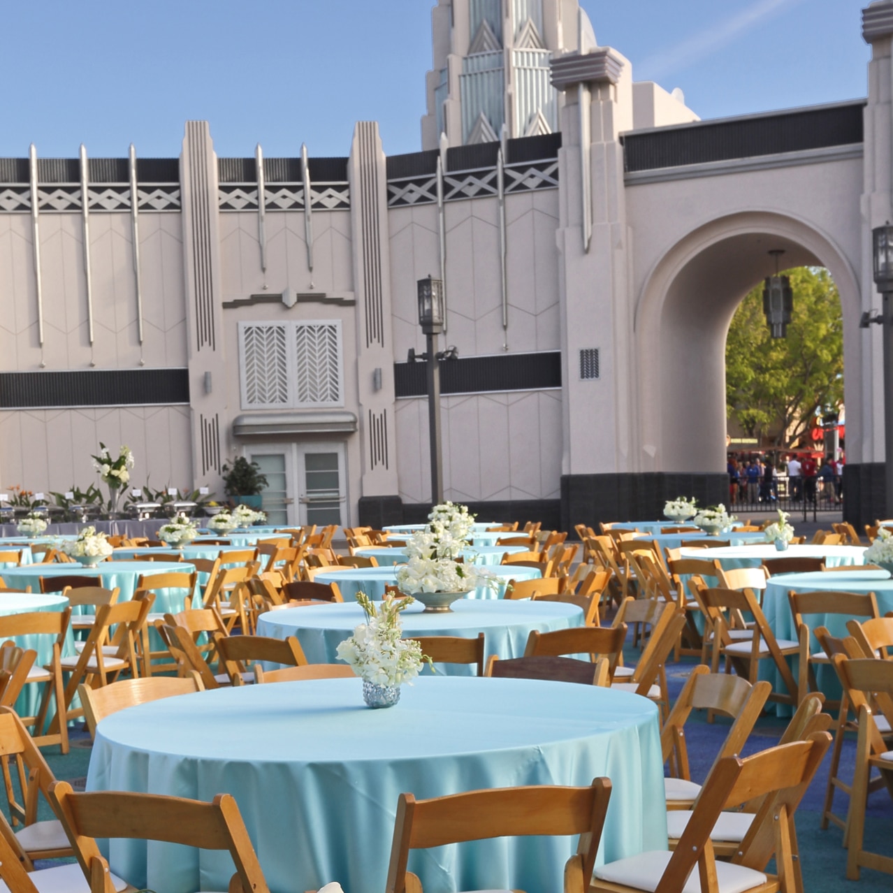 Tables with teal tablecloths and floral centerpieces set up for an event inside of Universal Plaza.