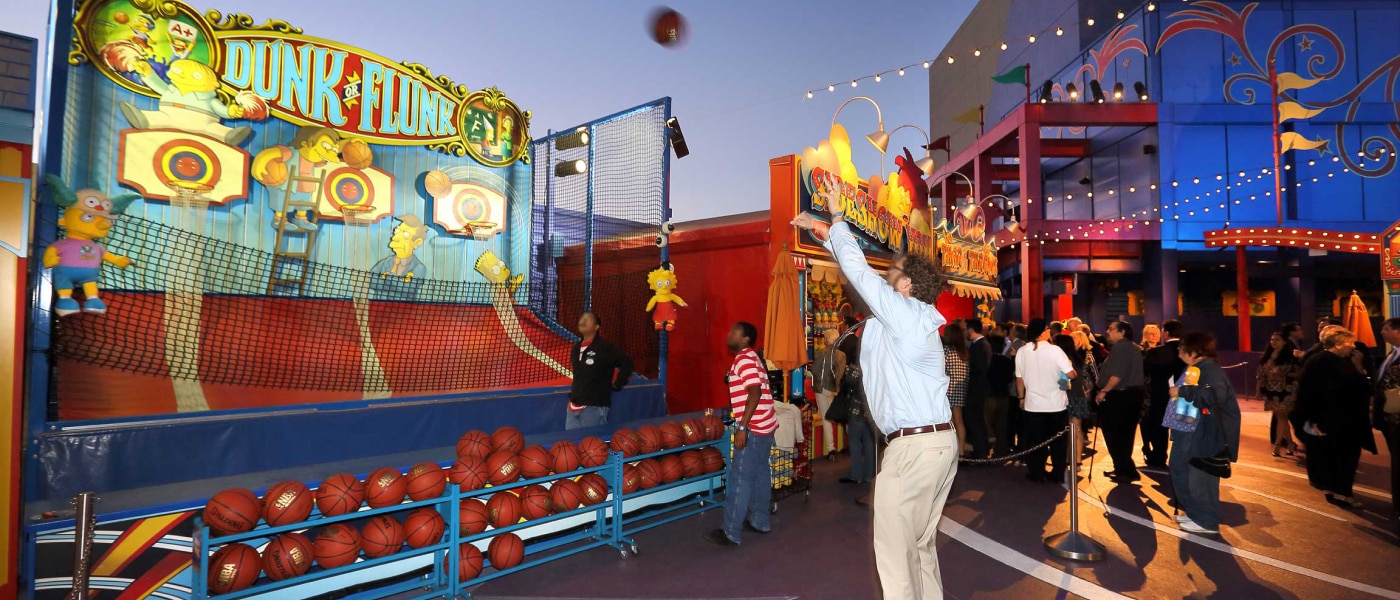 A guest trying their shot at a basketball hoop carnival game near Krustyland.