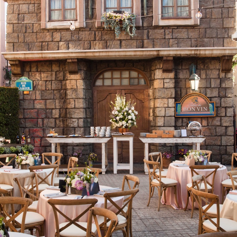 A Parisian building with tables and flowers set up outside.