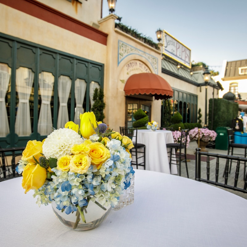 A close up of a white table topped with a blue, white and yellow floral arrangement.