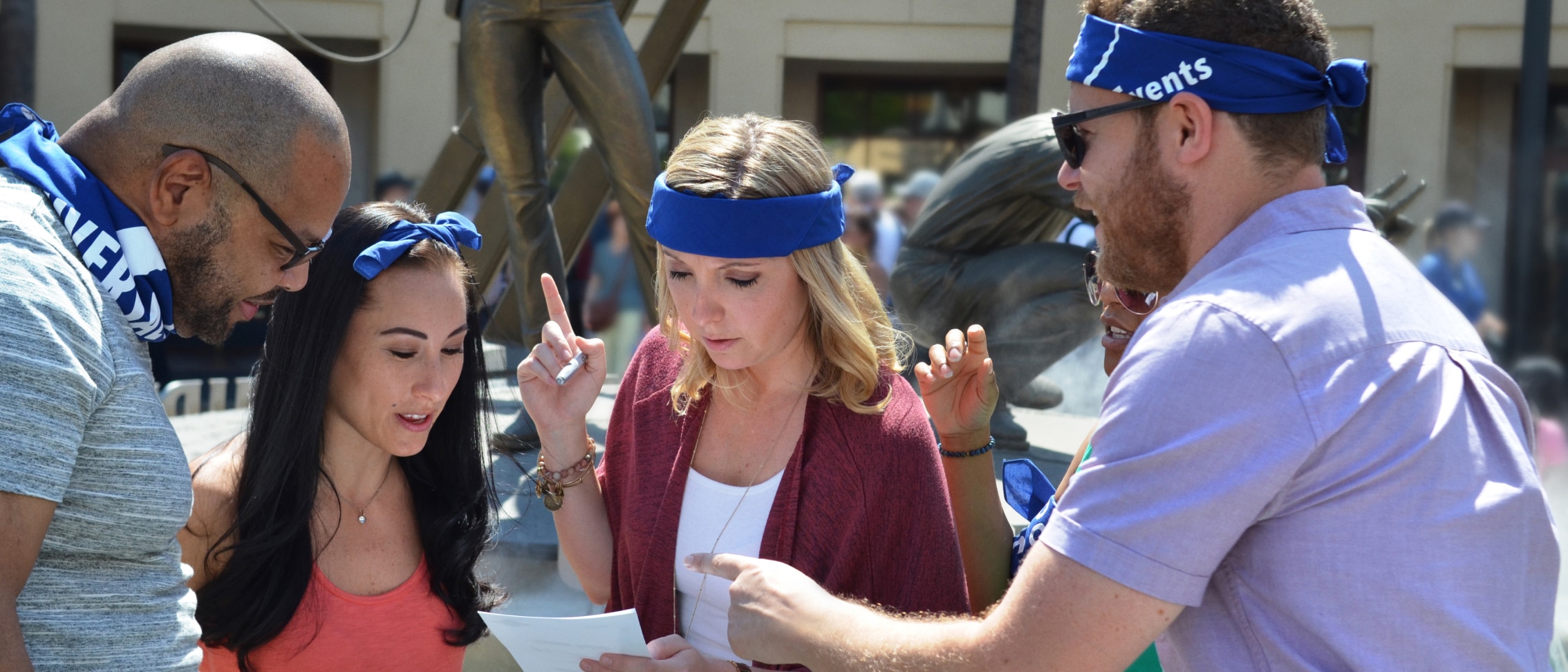 Four coworkers wearing blue bandanas as they work together during a team building activity at Universal Studios Hollywood.
