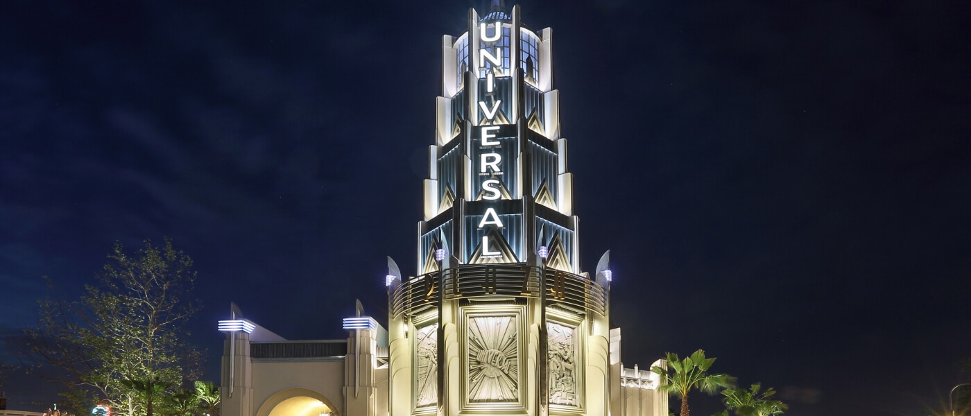 Illuminated Universal Studios Hollywood tower entrance at night with Art Deco architecture.