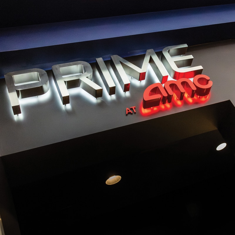 PRIME at AMC® sign in white and red on an overhead wall display.