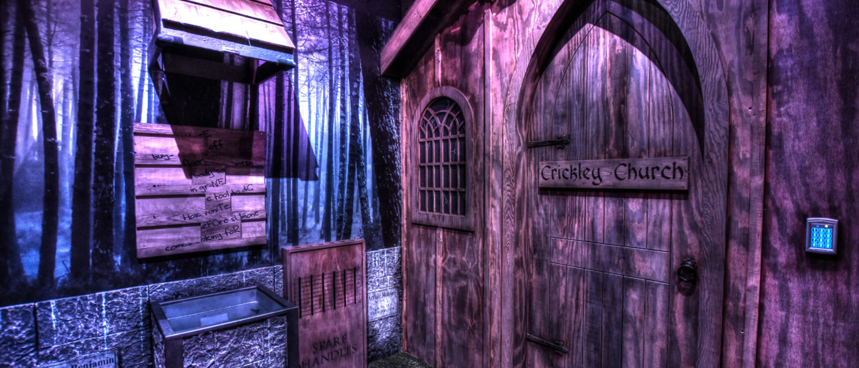 A church-themed room consisting of a walls with trees on it and a wooden door with the words: Crickley Church on it.