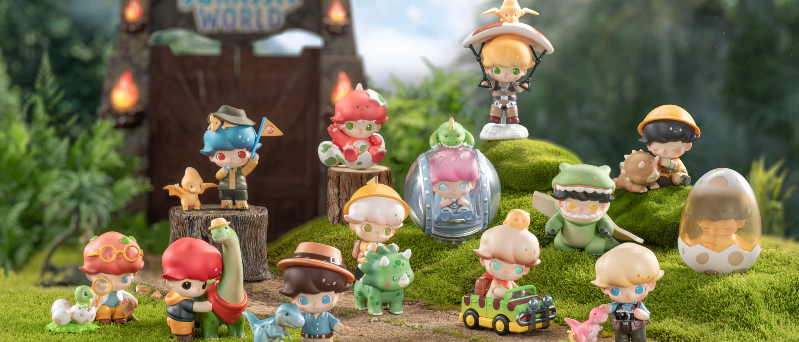 The 13 toy dolls in the Jurassic series posing in a lawnscape with the ‘Jurassic World’ entry gate behind them.