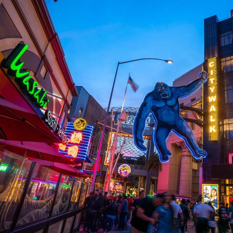 Groups of guests walking past various restaurants and a King Kong cutout hanging from a CityWalk sign.