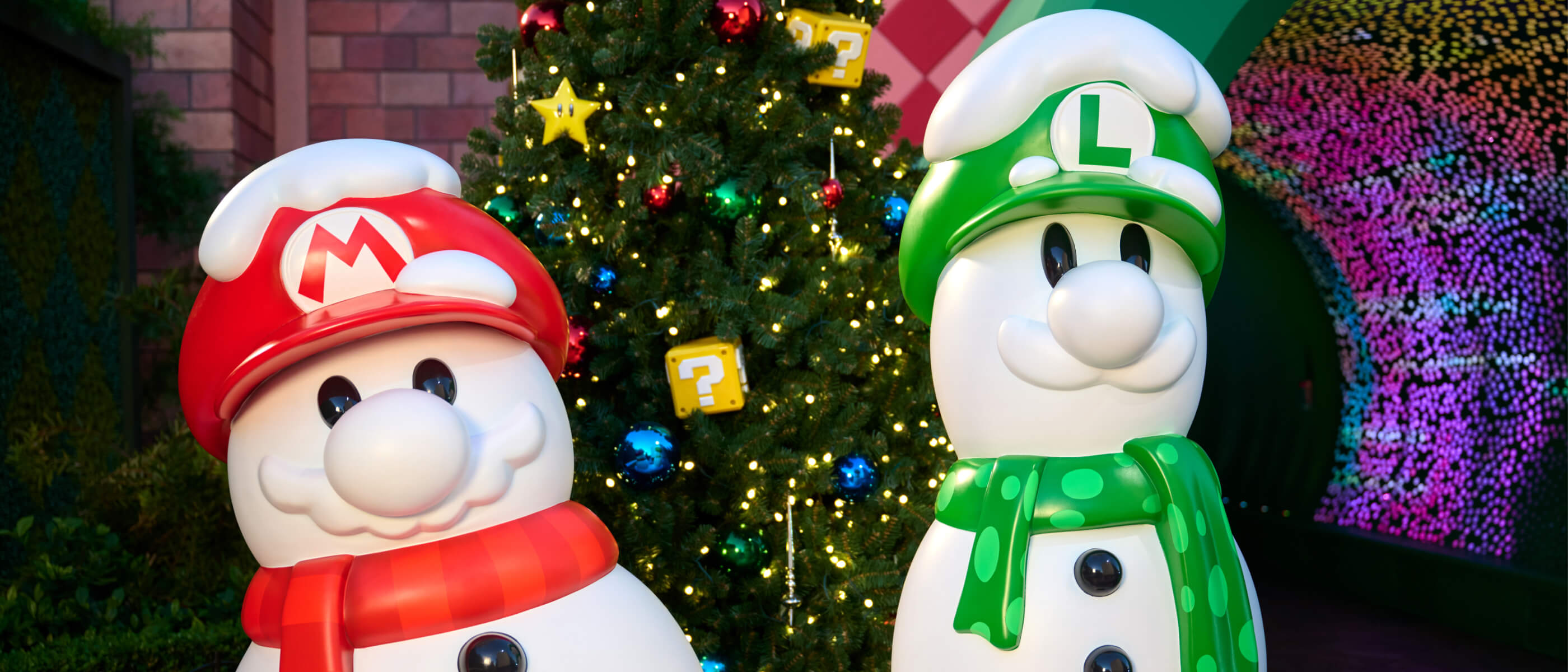 Mario and Luigi snowmen in front of a Christmas tree in SUPER NINTENDO WORLD at Universal Studios Hollywood.