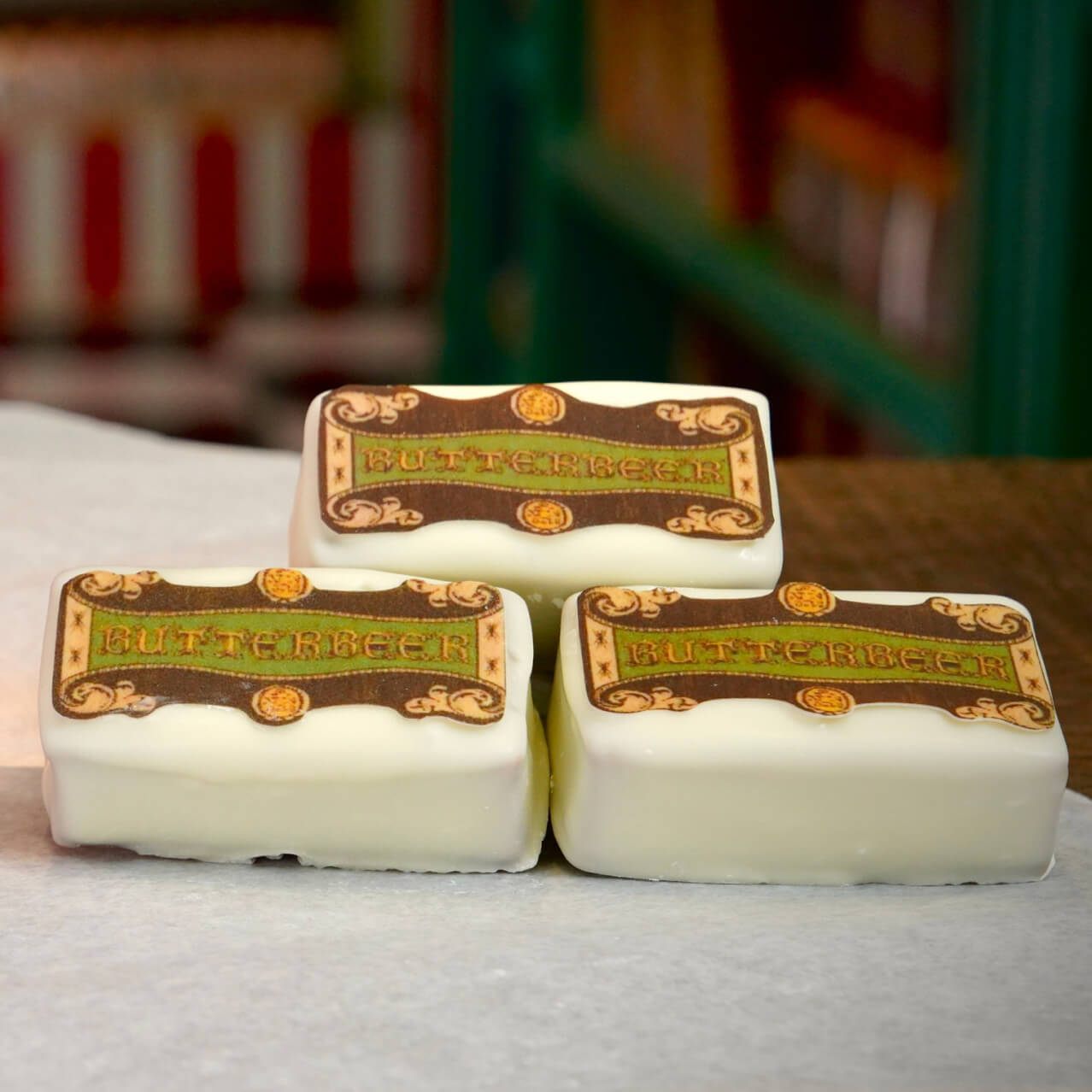 A plated puff pastry topped with decorative cream and a “BUTTERBEER” sign, on a wooden table with windows in the background.
