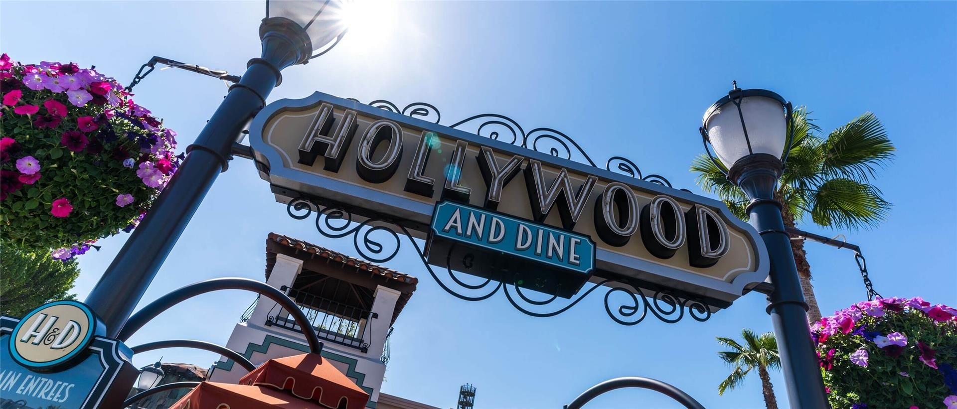 The Hollywood and Dine sign with flowers on the side on a sunny day.