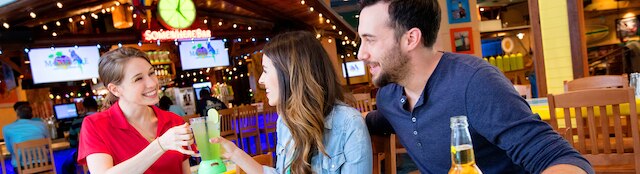 A waiter handing over a Margarita to a couple at Margaritaville