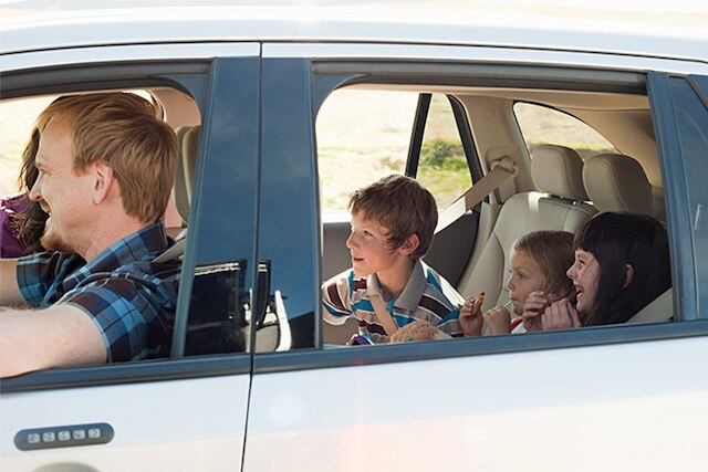 A family takes a drive with the windows down.
