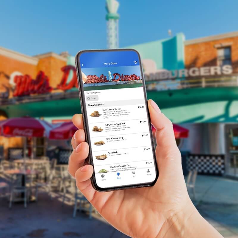 Person holding a phone with the Universal Studios Hollywood App in front of a restaurant.