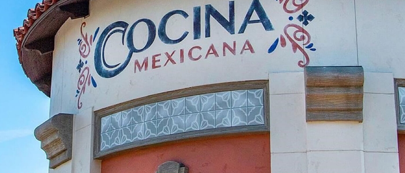 The words “COCINA MEXICANA” in blue and red with accent marks under a terracotta roof reminiscent of Mexican architecture.