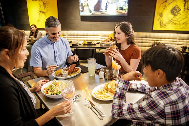 A family of four dining inside a restaurant and enjoying their meal together.