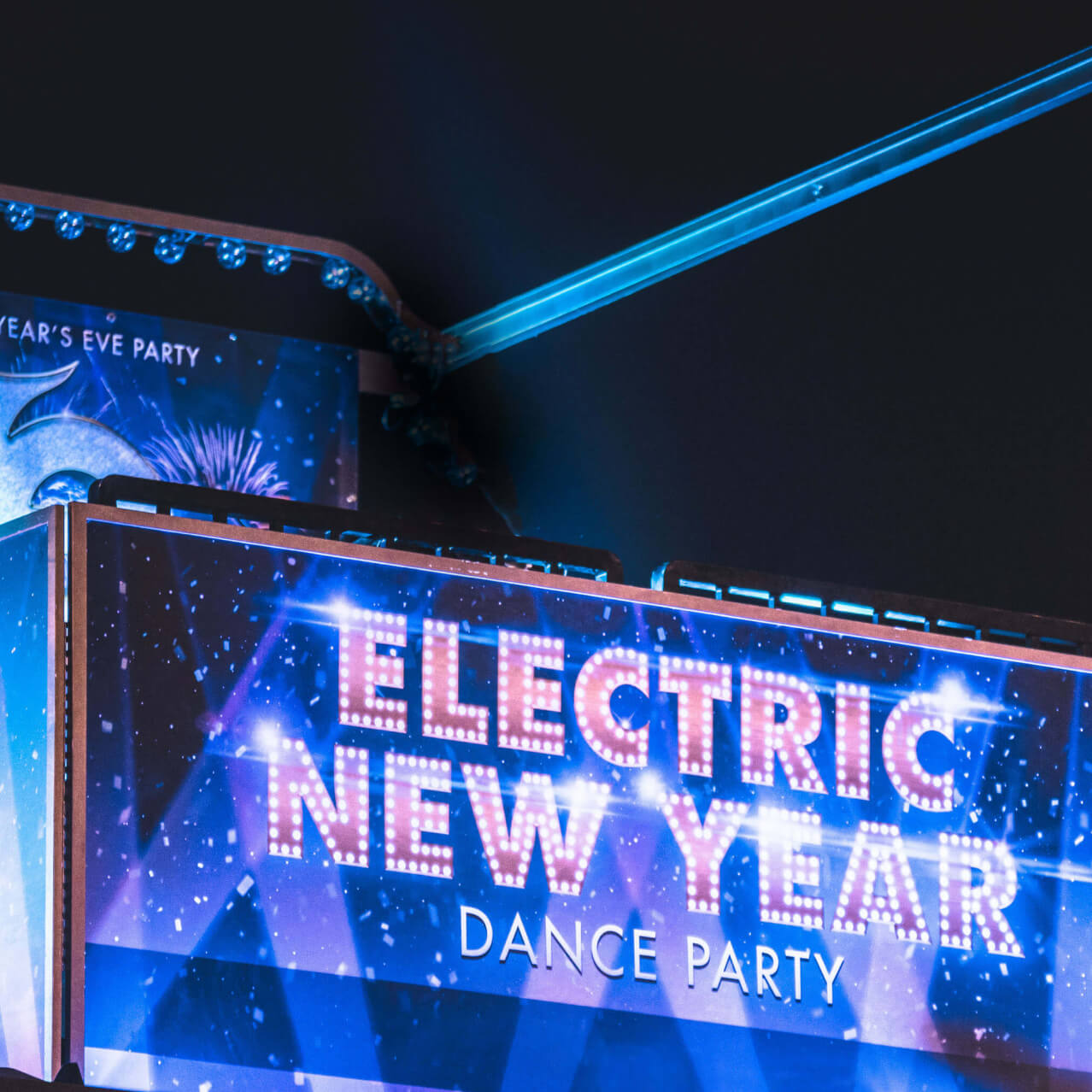 A neon sign reading Electric New Year lights the way to a party area at Universal Studios Hollywood’s EVE event.