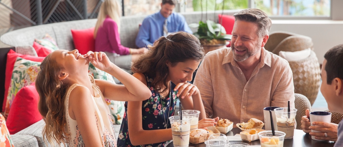 Family sitting at a table eating and laughing.