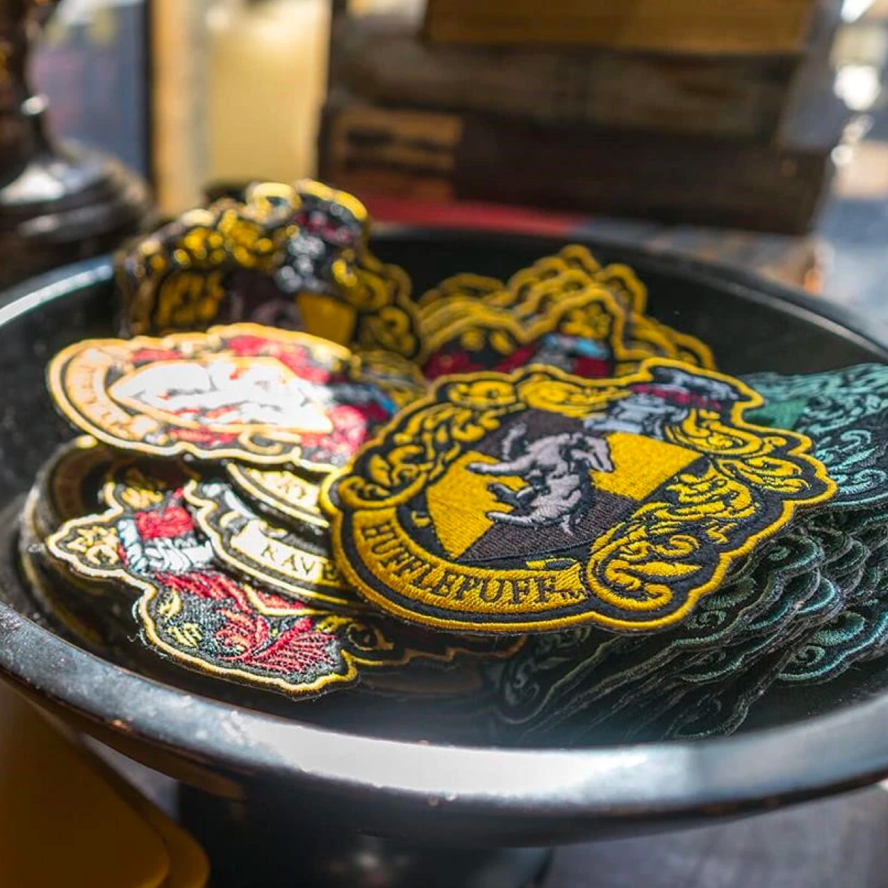 A bowl holding with the Hogwart houses symbols on them.