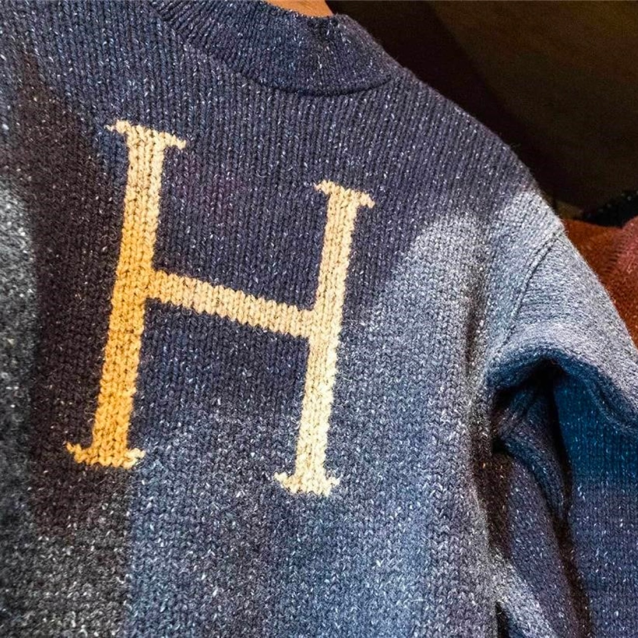 Up Close to two knitted sweaters hanging, one is blue with a H and one is red with a R.