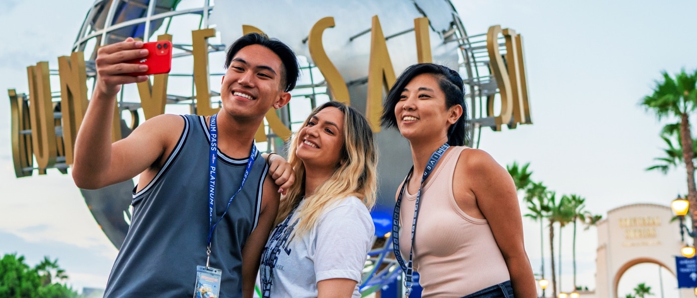 Three people taking a selfie in front of the Universal Studios globe.