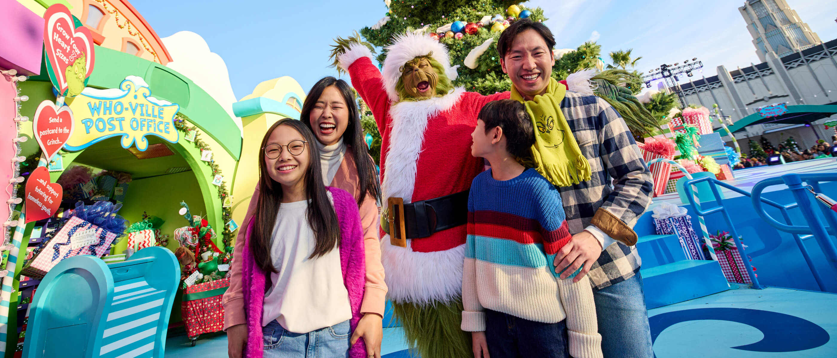 A family of four posing with the Grinch in front of a Christmas tree in Whoville.