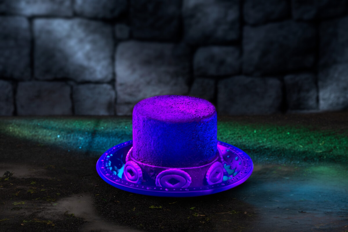 A purple dessert in the shape of a decorative top hat against a green carpet and dark stone wall background.