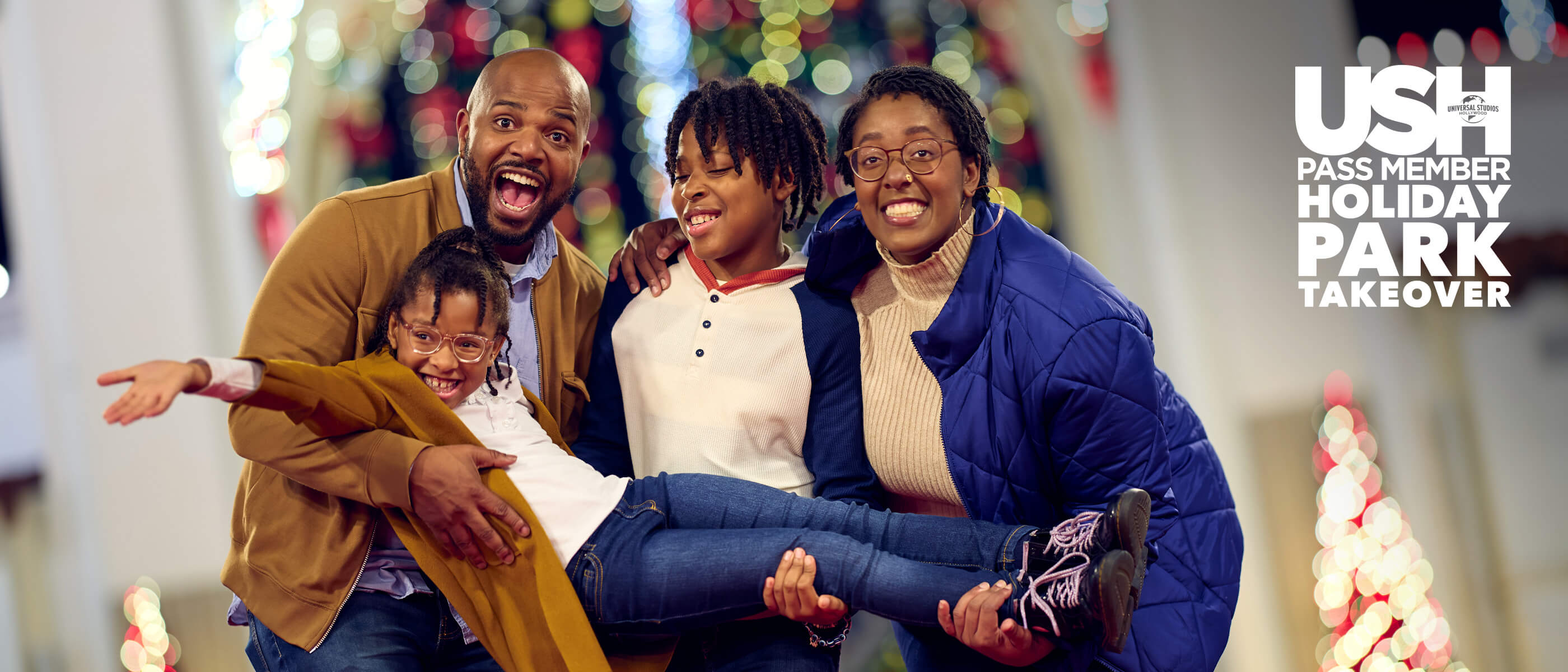 A family of four, three of them holding the youngest, enjoying Universal Studios Hollywood Pass Member Holiday Park Takeover.
