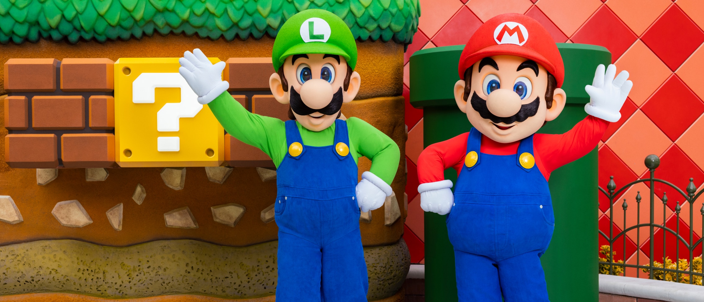 Nintendo characters Luigi and Mario each gesture with one arm at SUPER NINTENDO WORLD™.