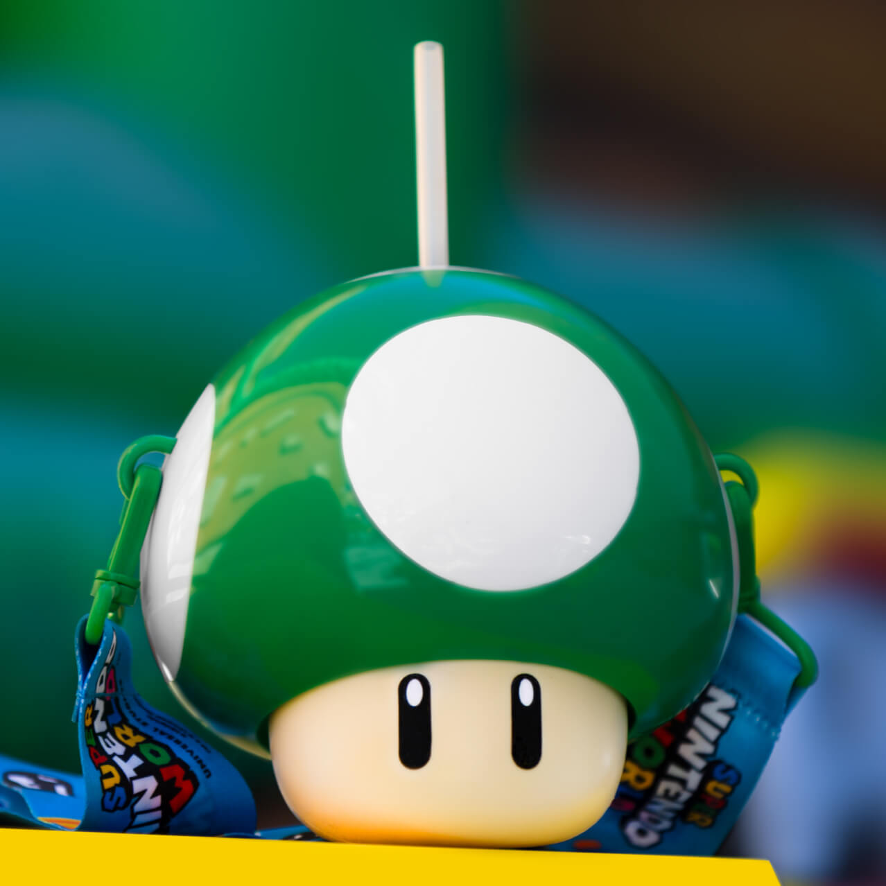 A drink container shaped like a 1-UP Green Mushroom from Super Mario. A straw sticks out the top.