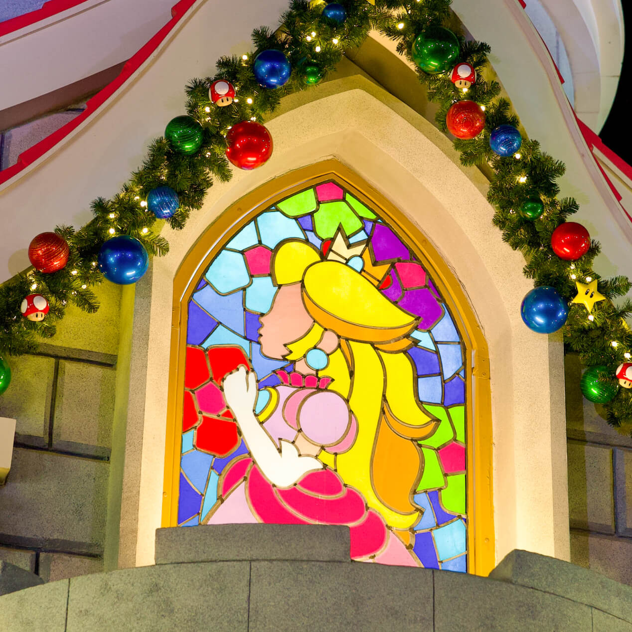A stained glass window at Princess Peach's Castle with holiday décor in SUPER NINTENDO WORLD™ at Universal Studios Hollywood.
