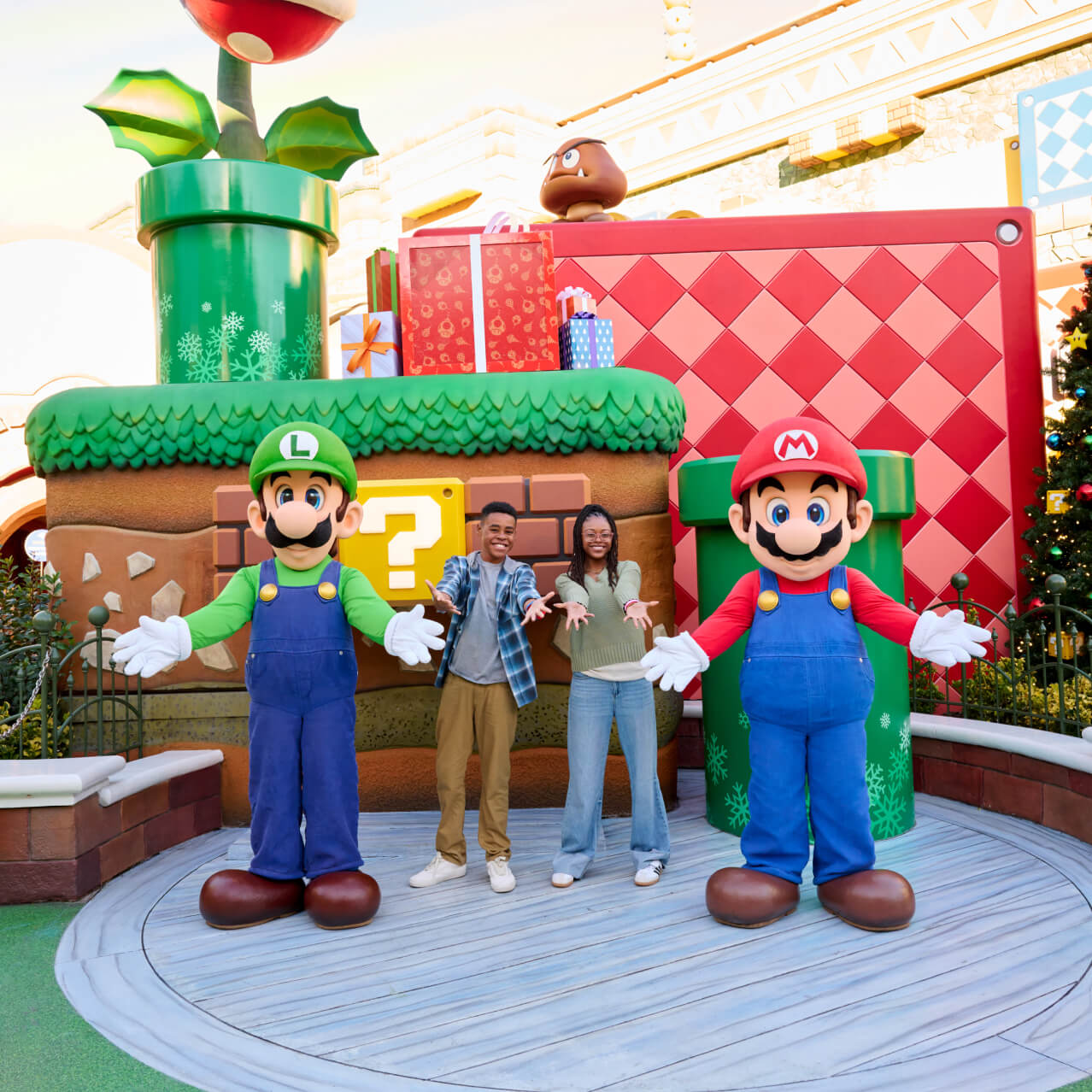 Two guests smiling during a character meet and greet with Mario and Luigi, and all posing with their arms outstretched.