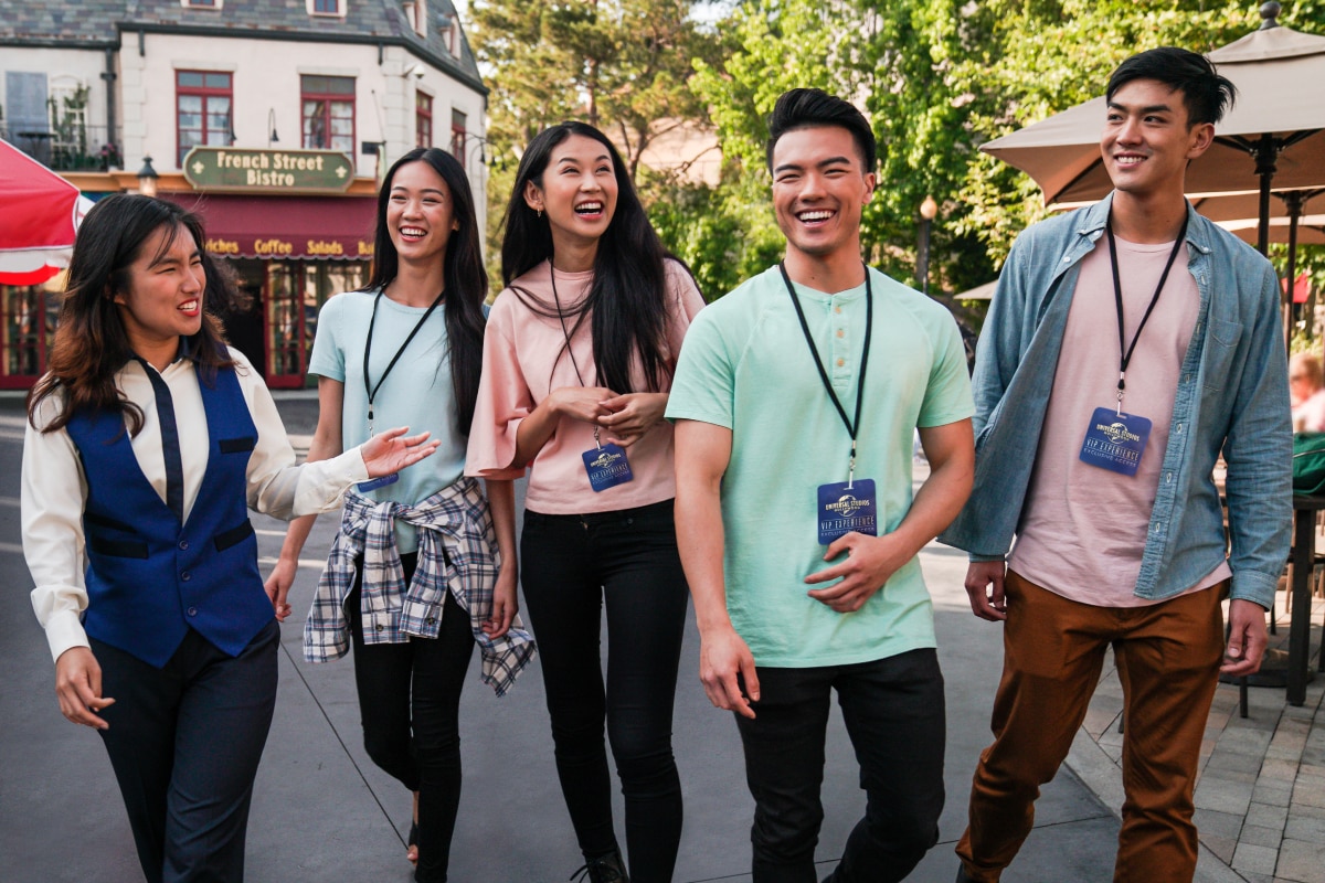 Four friends wearing blue VIP Experience lanyards smiling and laughing while walking with a tour guide in a blue vest.
