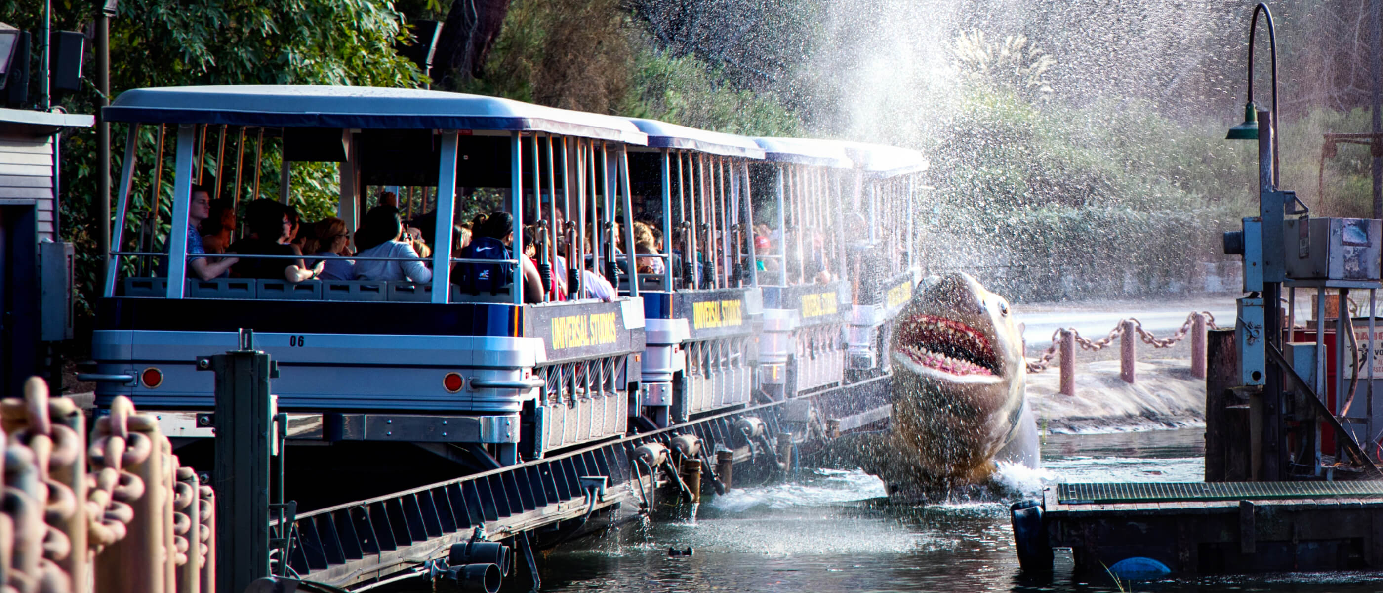 A shark coming out of the water next to a tram full of people.
