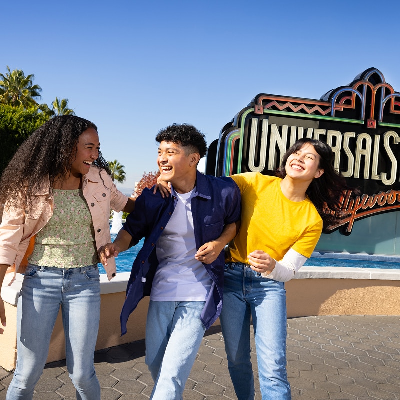 Three individuals smiling in front of a Universal Studios Hollywood sign